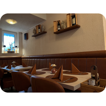 Innenansicht Restaurant Apollo - Rechts vom Eingang. Ristorante Apollo in Blomberg. Gemütlicher Restaurantbereich mit gedeckten Tischen und braunen Lederbänken.