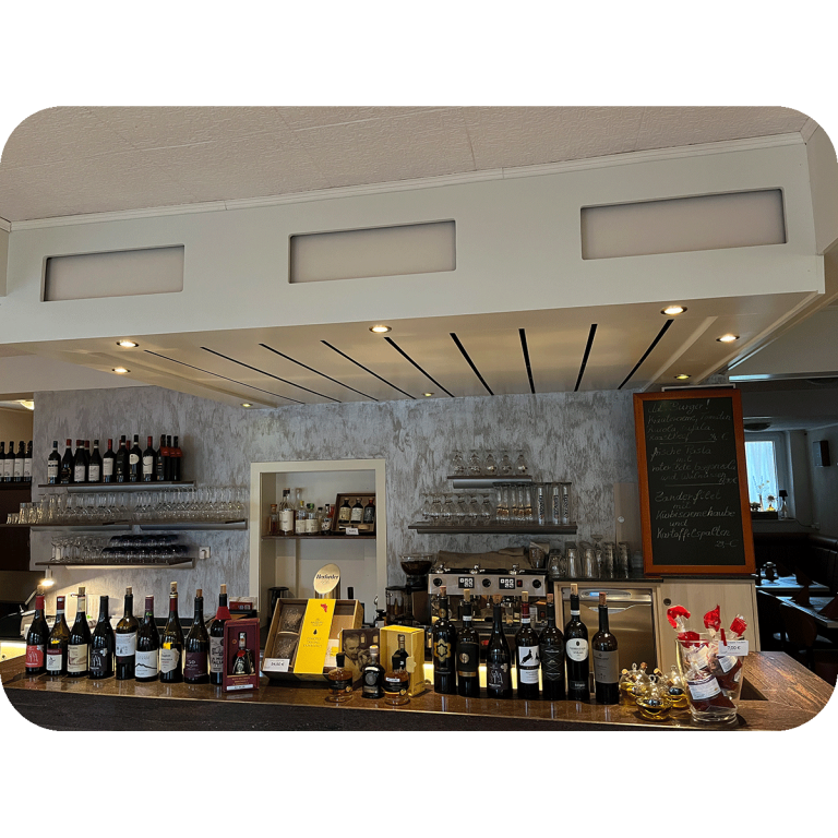 Innenansicht Restaurant Apollo - Theke Ristorante Apollo in Blomberg. Moderne Bar mit Regalen, Weinen, Spirituosen und einer Tafel im Hintergrund.